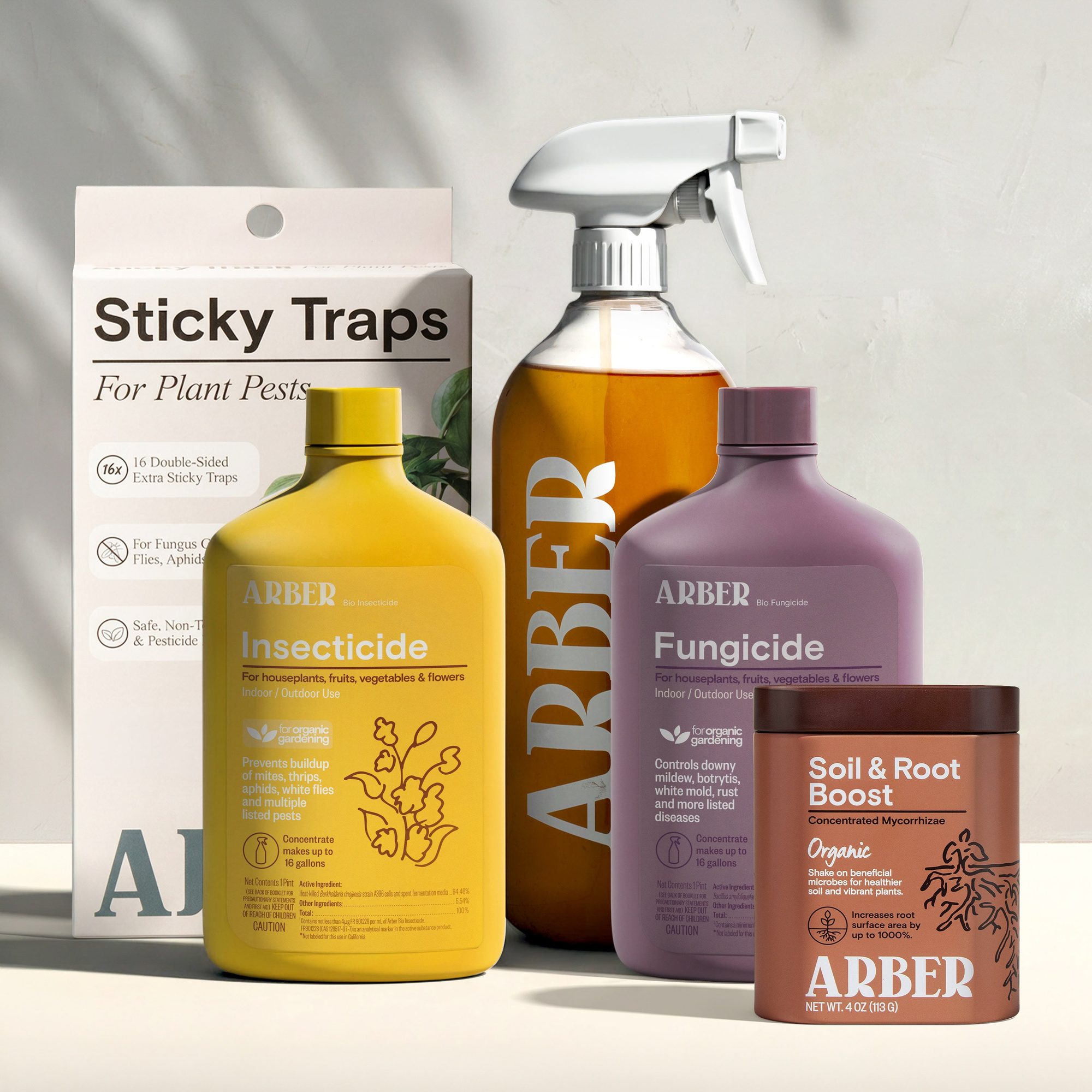 Sticky traps package and plant care product bottles including yellow insecticide, brown spray bottle, purple fungicide, and terracotta root boost container displayed on white surface