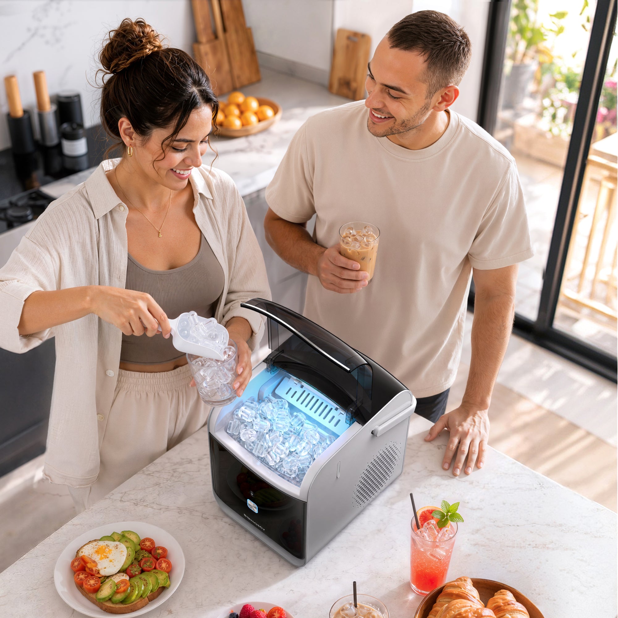 Couple in kitchen using a portable ice maker while preparing drinks and food